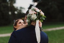 bride rests flowers behind grooms head